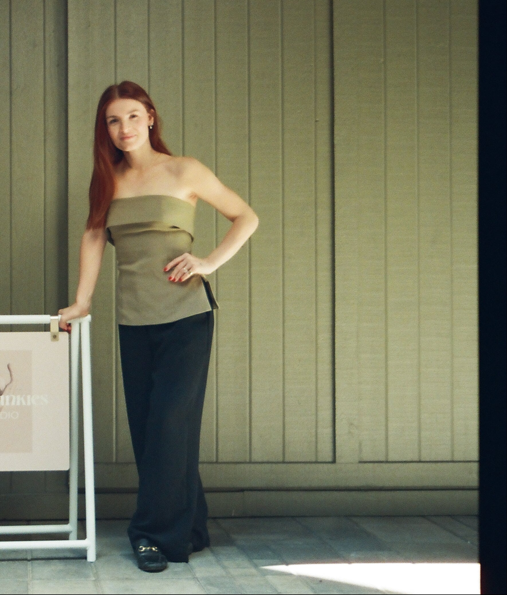 Two women standing next to a framed picture against a green wall.