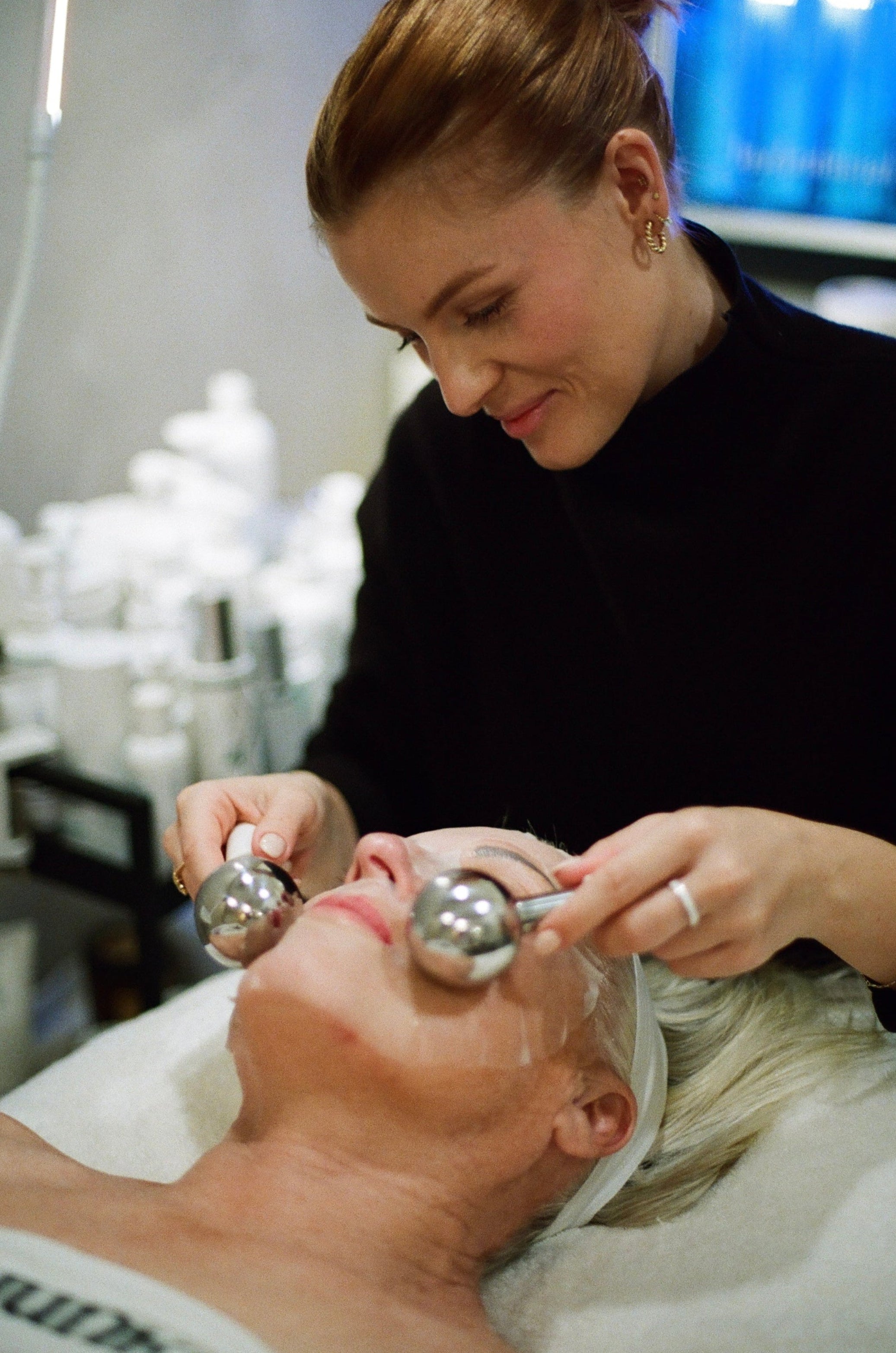 Woman receiving a facial treatment with a professional in a clinical setting.